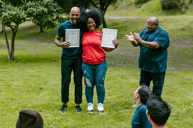 graduates celebrate with certificates outdoors